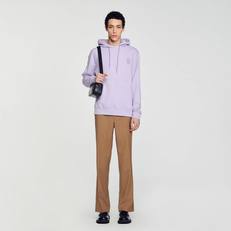 Purple hooded sweatshirt with a floral embroidery, worn by a man with brown trousers and shoes.