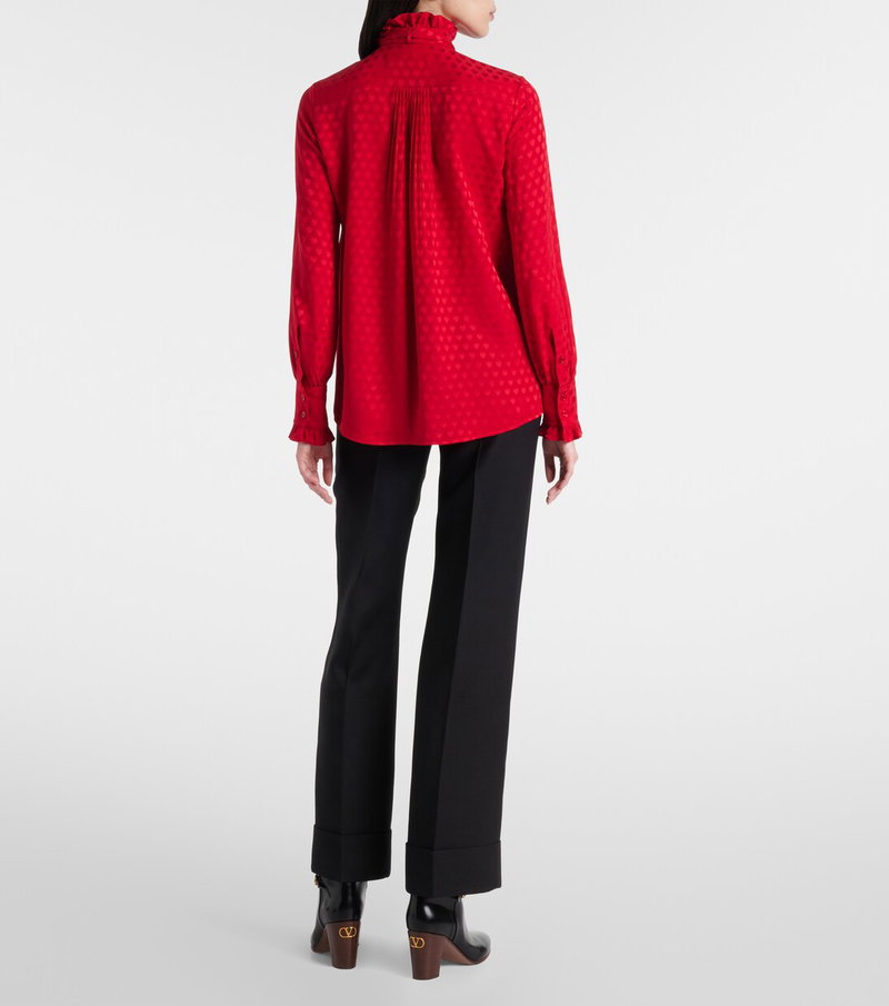 Red Valentino silk blouse with ruffled neckline and wide-leg black trousers.