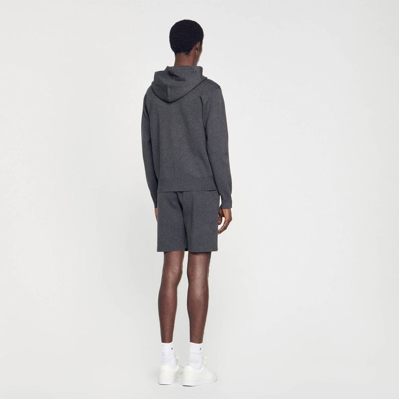 Man wearing a gray SANDRO hoodie and shorts.