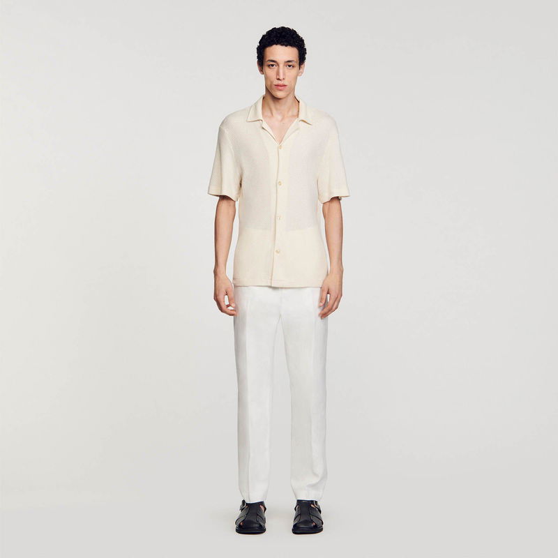Man wearing a beige ribbed knit shirt and linen trousers.