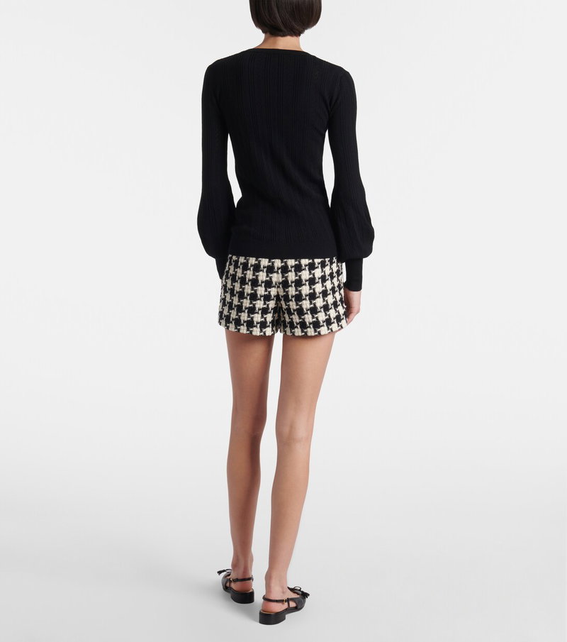 Black ribbed sweater with puffed sleeves, paired with houndstooth shorts.