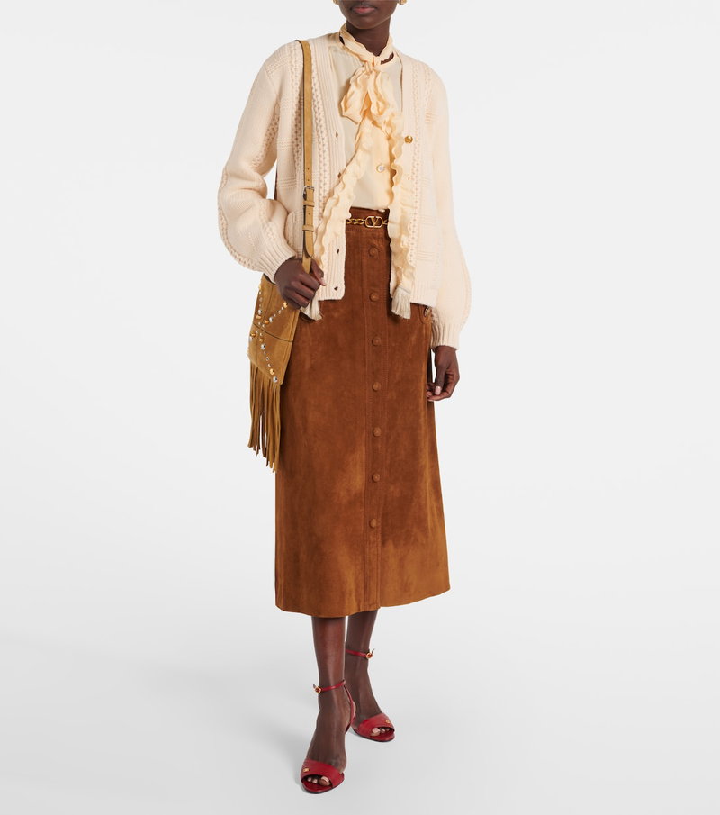 Cream cable-knit cardigan with gold chain belt over suede skirt