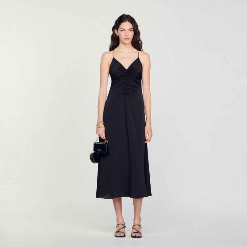 Black satin midi dress with ruched bodice, worn by a woman.