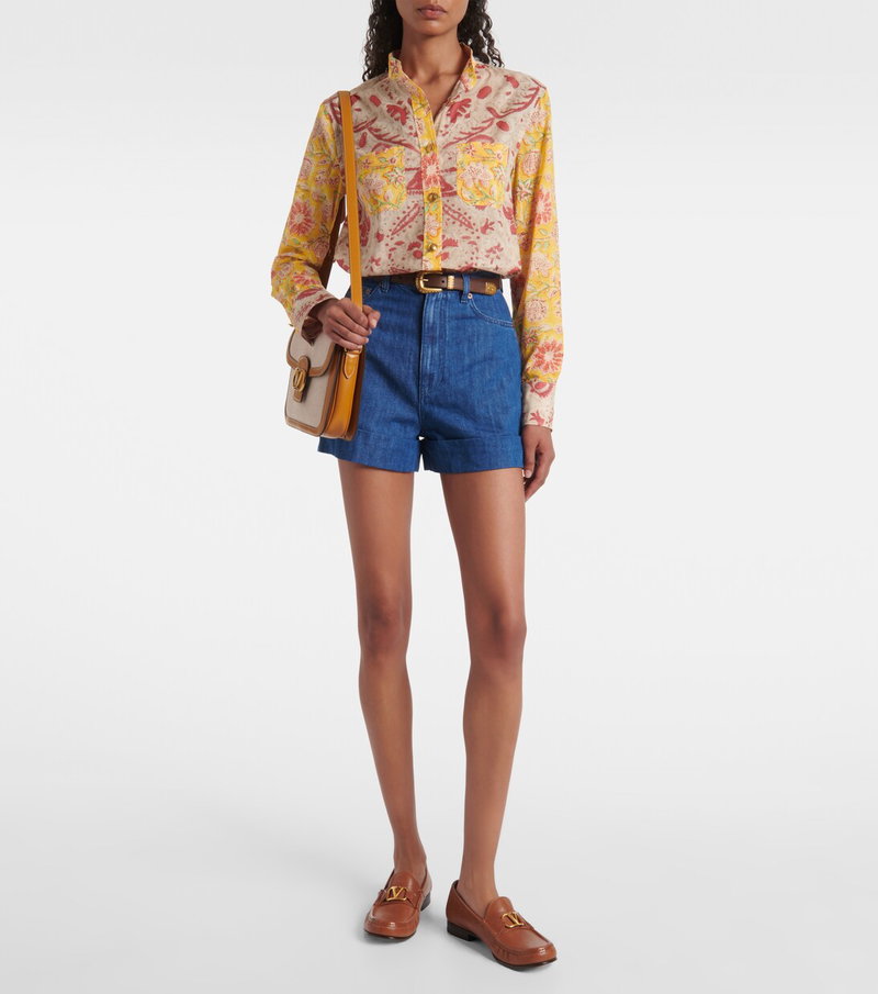 Valentino woman in floral shirt, denim shorts, and loafers.