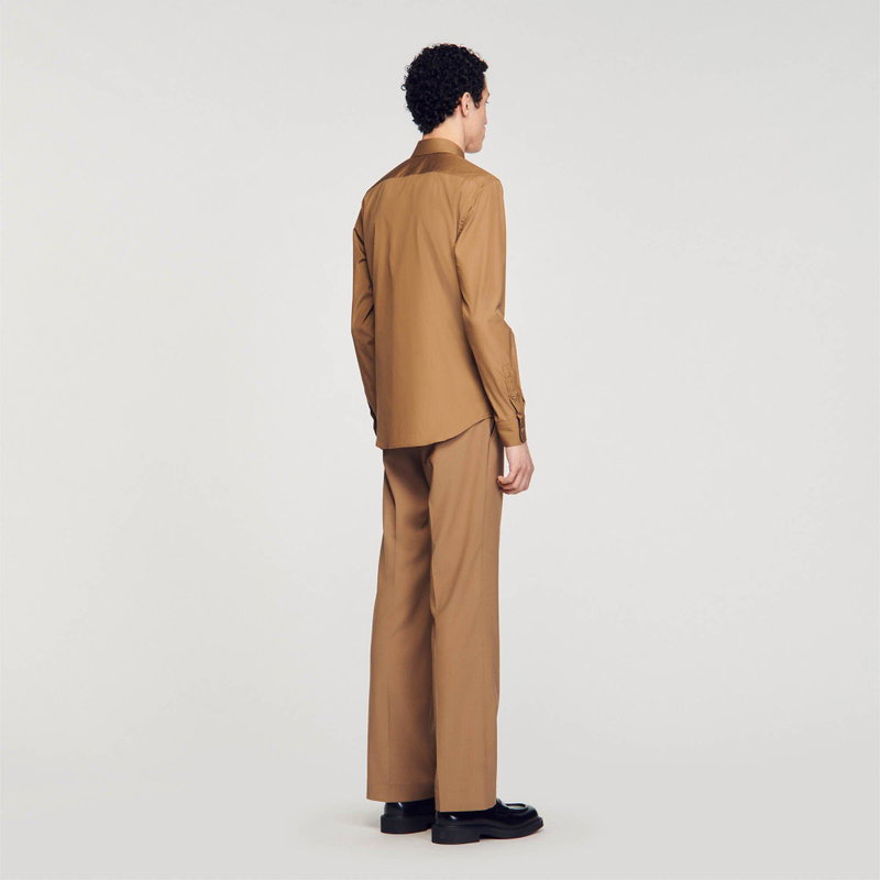 Man wearing a brown shirt and trousers.