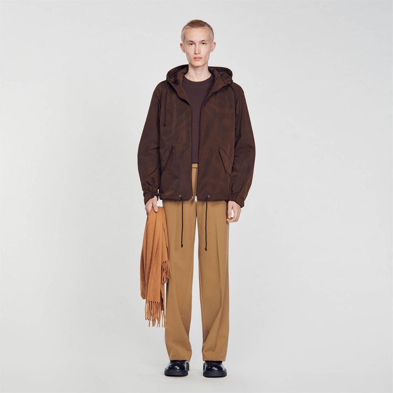SANDRO - Man in brown hooded jacket, trousers, and scarf.