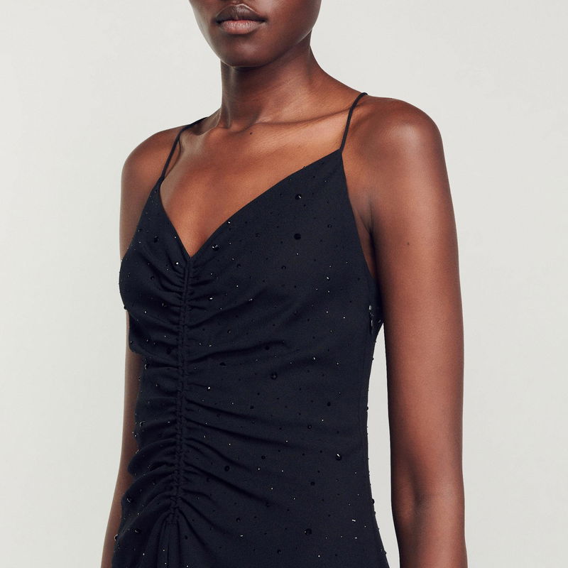 Black satin slip dress with beaded embellishments and a ruched bodice.