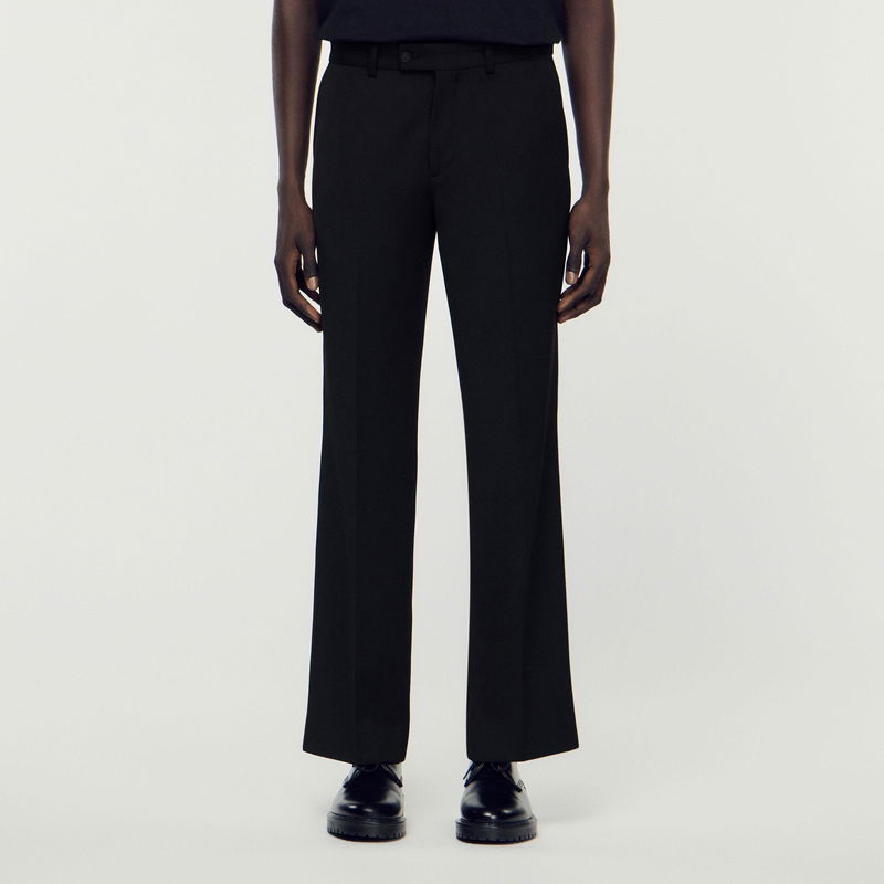 Black wool trousers with a front button and a person wearing them.