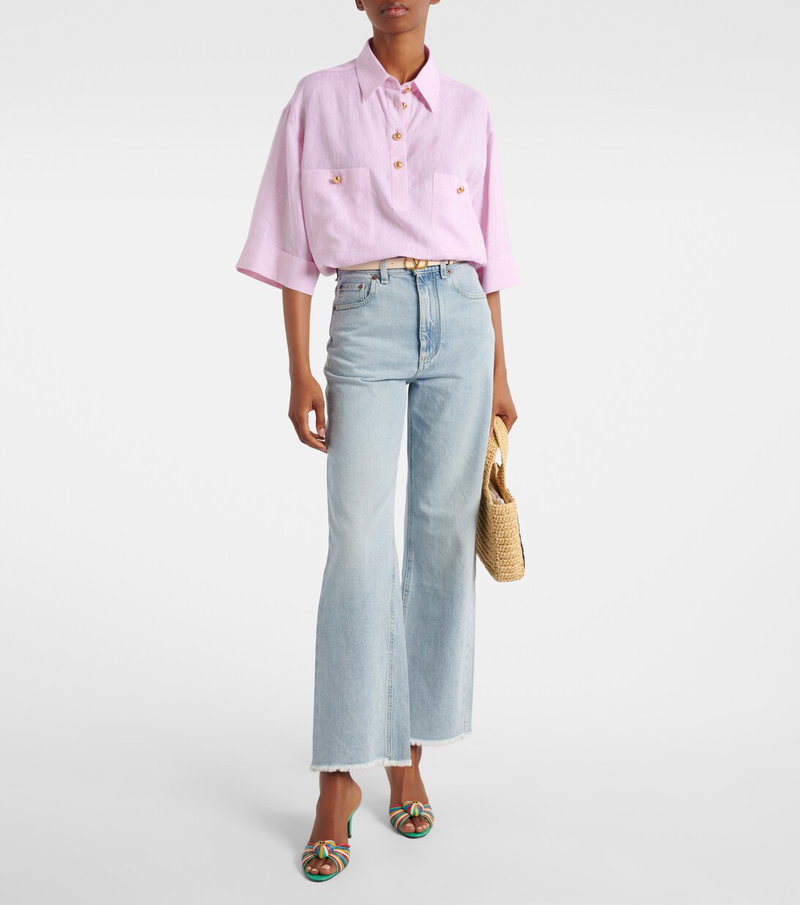Pink linen shirt with gold buttons, paired with wide-leg jeans and a woven bag.