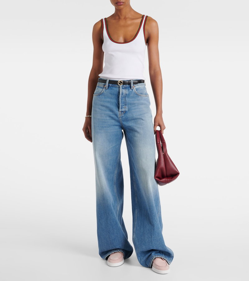 White ribbed tank top with red trim, paired with wide-leg denim jeans and a burgundy tote.
