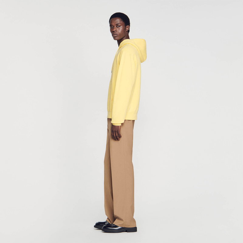 SANDRO - Man in yellow hooded sweatshirt and brown trousers