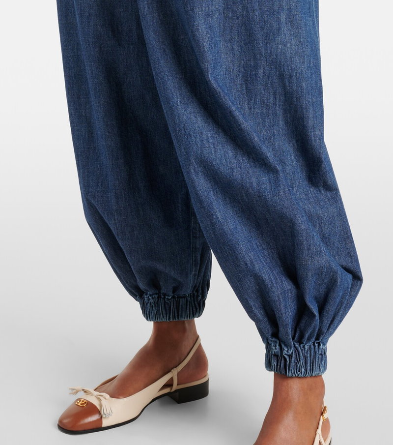 Valentino wide-leg denim trousers with a gold logo and leather sandals.