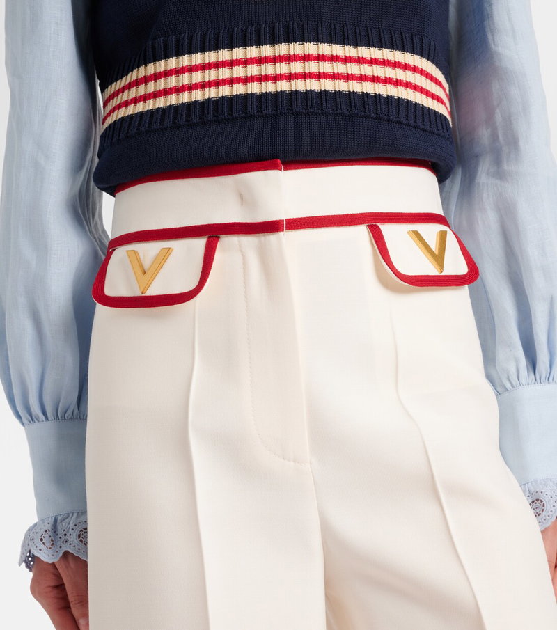 Valentino navy knit top with red and white stripe belt and white trousers featuring a gold V buckle.