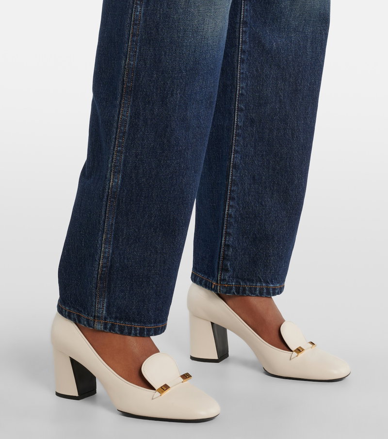 Cream leather pumps with gold hardware, paired with wide-leg denim.