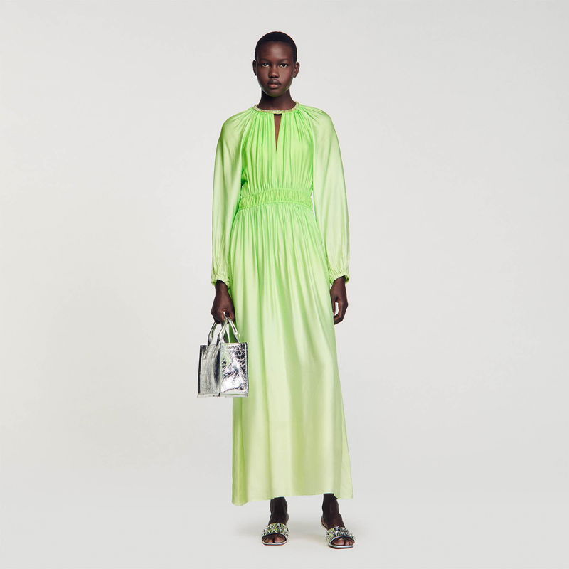 Lime-green silk dress with puffed sleeves and a model holding a silver bag.
