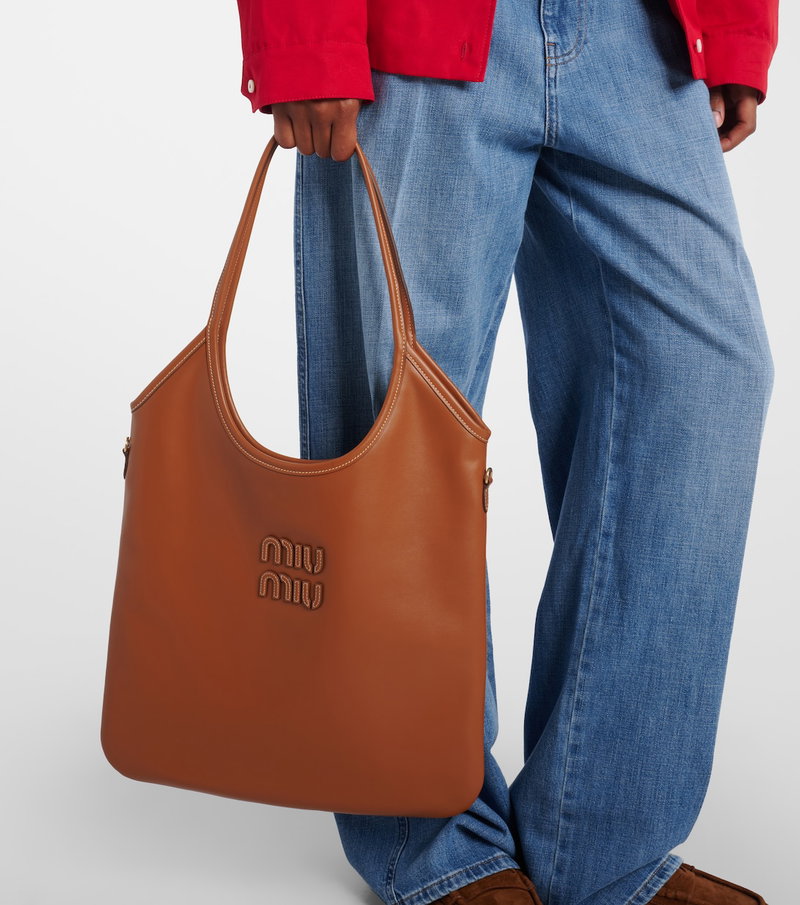 Brown MIU MIU hobo bag with logo detail, worn by a person.