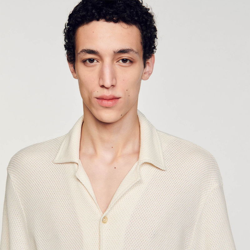Man wearing a textured cream-colored cardigan.