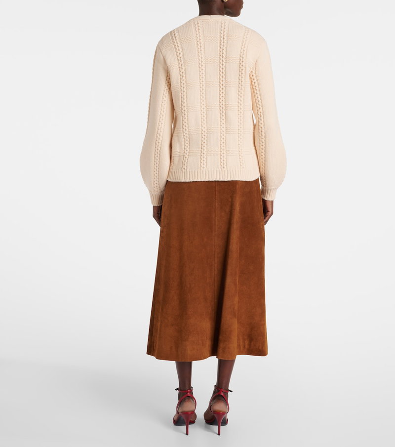 Cream cable-knit sweater with brown suede skirt and red heels