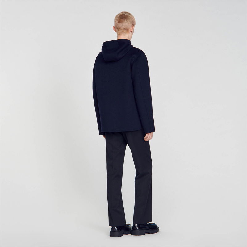 Dark grey hooded sweater with black trousers.