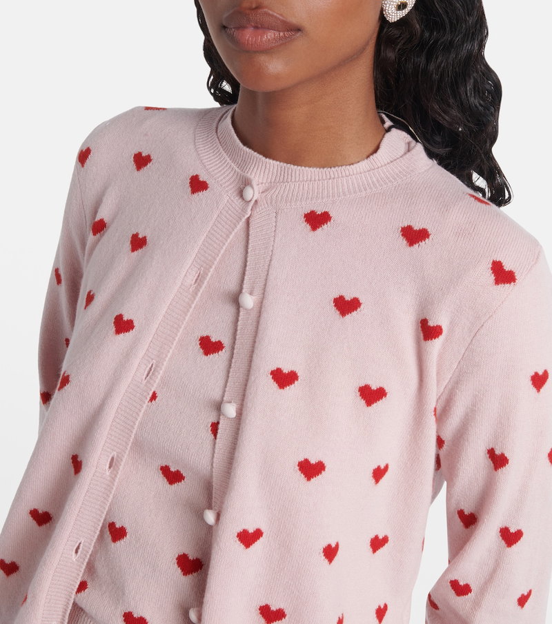 Pink cardigan with red heart embroidery, worn by a woman.
