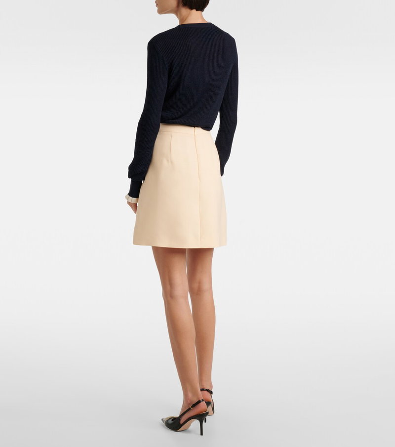 Dark navy sweater and pale beige skirt.