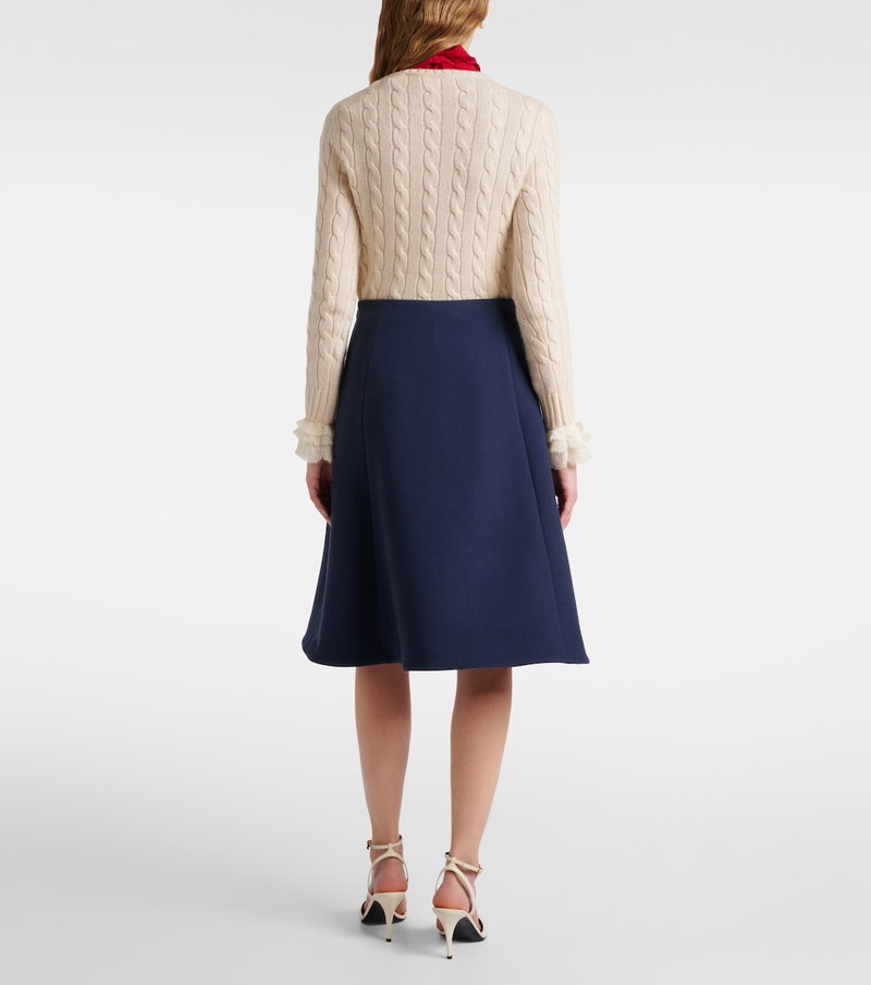 Cream cable-knit sweater with navy pleated skirt