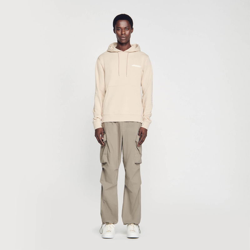 Man in SANDRO beige hoodie and olive cargo pants
