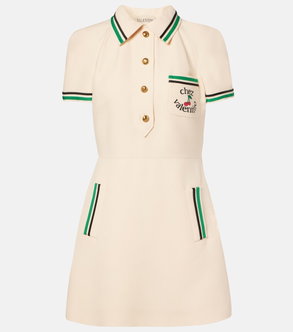 Cream-colored polo dress with green trim and cherry emblem