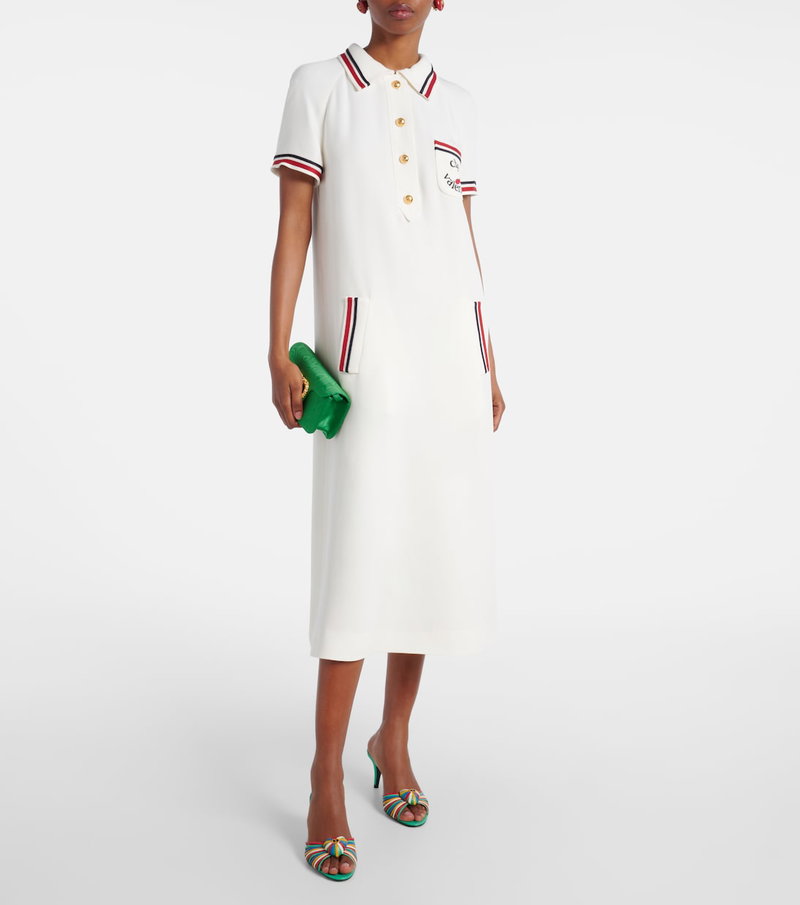 White polo dress with red and white stripes, Valentino logo, and a green clutch.