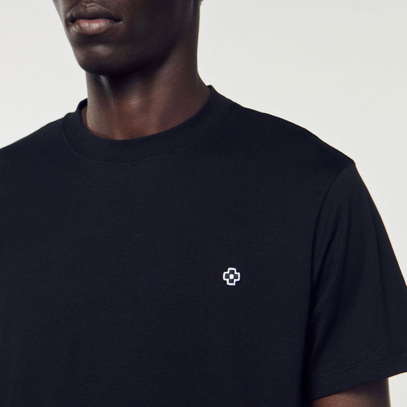 Black t-shirt with a white cross emblem on the chest.
