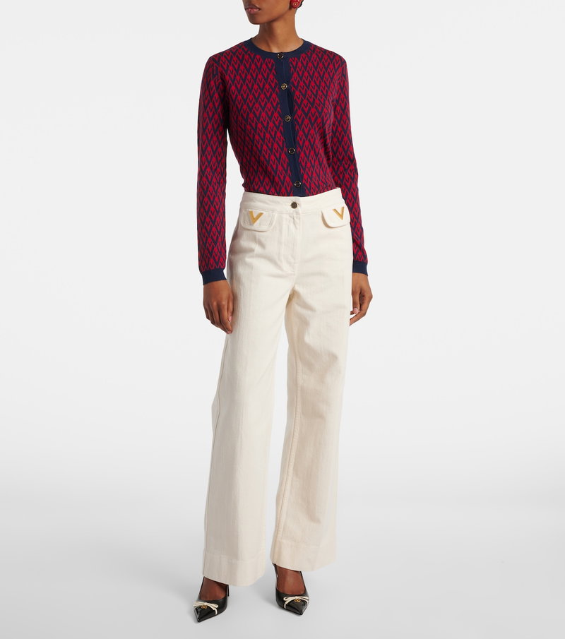 Valentino red and navy diamond-patterned cardigan over cream wide-leg trousers.