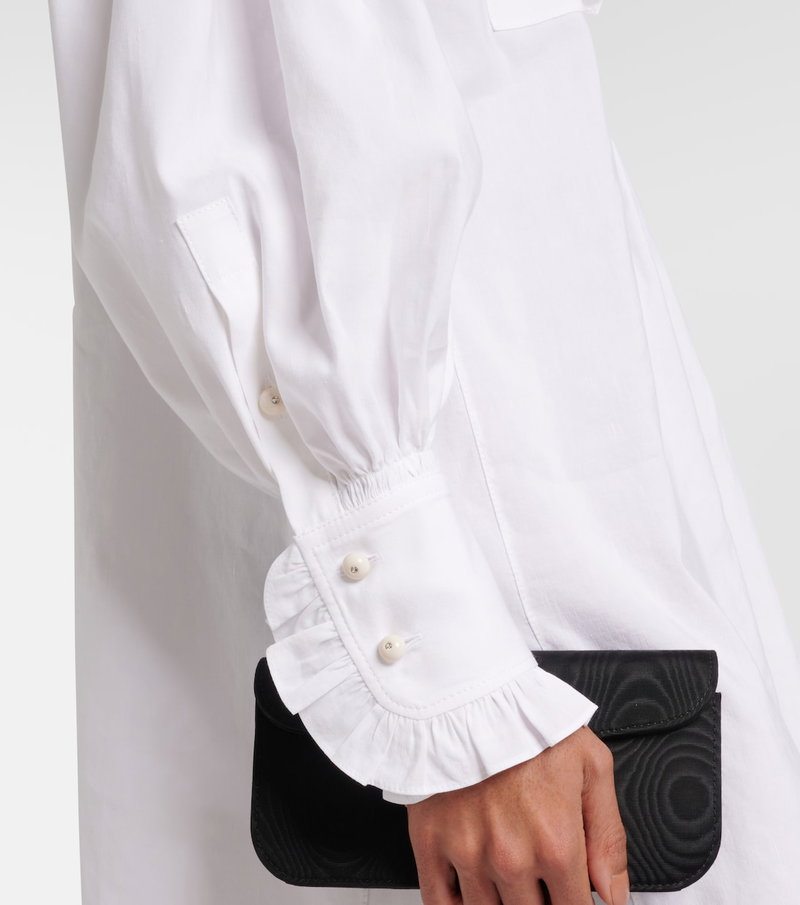 White button-down shirt with ruffled cuffs and a black clutch.