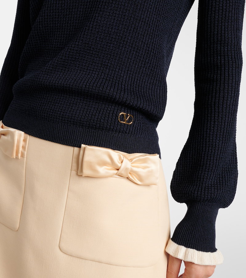 Navy ribbed sweater with a satin bow waistband.