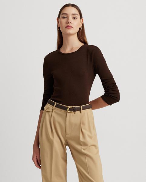 Woman wearing a brown long-sleeved top, brown belt, and beige pleated trousers.