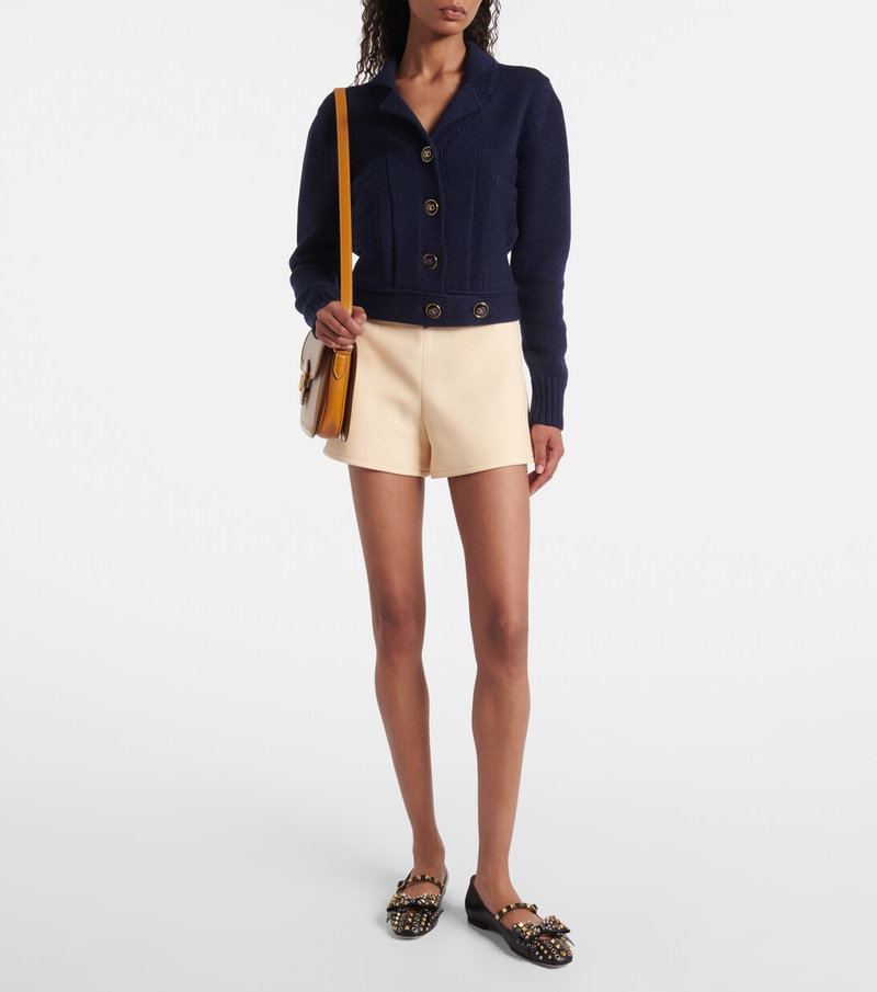 Navy cable-knit cardigan and cream tailored shorts with Valentino accessories