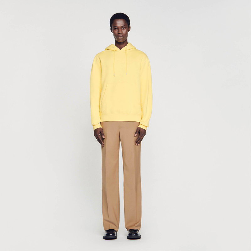 Man in a yellow hooded sweatshirt and beige trousers.