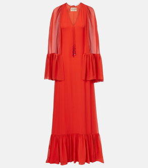 Red gown with sheer, draped sleeves and ruffled skirt.