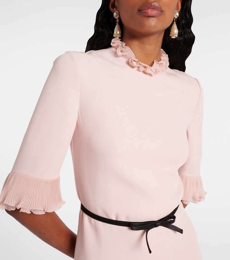 Pink ruffled blouse with pleated sleeves and a satin belt, featuring a model's neck and earrings.