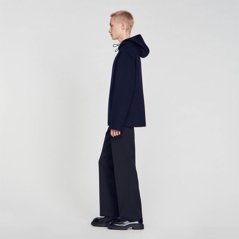 Dark blue hooded sweater with drawstring and wide-leg trousers.