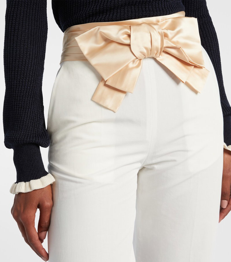 Valentino satin belt with a large bow, paired with white trousers.