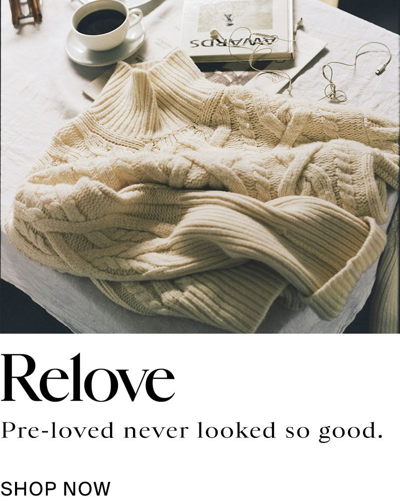 Cream jumper on table with cup of coffee. Relove, pre-loved never looked so good. Shop now.